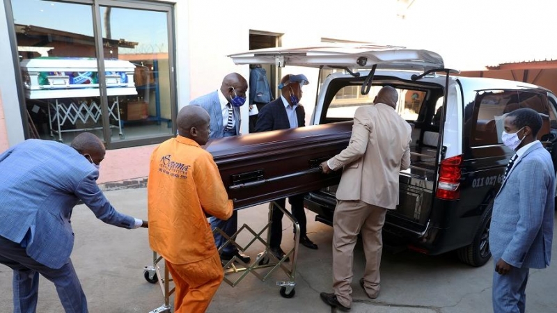 Operarios de una funeraria transportan un féretro en Sudáfrica. | REUTERS