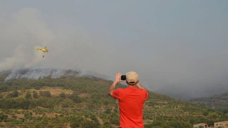 Un vecino de la localidad de Aldeanueva de la Vera (Cáceres) otografía los trabajos de extinción del incendio forestal declarado en Cabezuela del Valle, en la comarca cacereña del Valle del Jerte. / EFE/ Eduardo Palomo