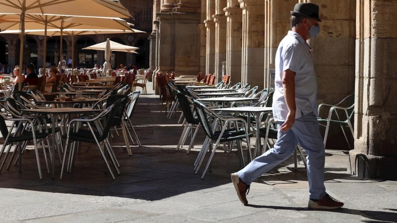 Un hombre con mascarilla pasa frente a una terraza de un restaurante de la plaza mayor de Salamanca, este miércoles. | EFE