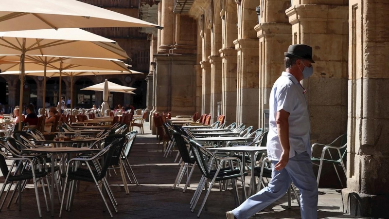 Un hombre con mascarilla pasa frente a una terraza de un restaurante de la plaza mayor de Salamanca, este miércoles. | EFE