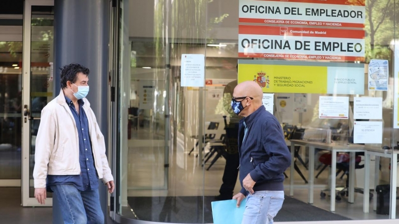 Dos personas con mascarilla pasan por una oficina de empleo de Madrid. E.P./Marta Fernández