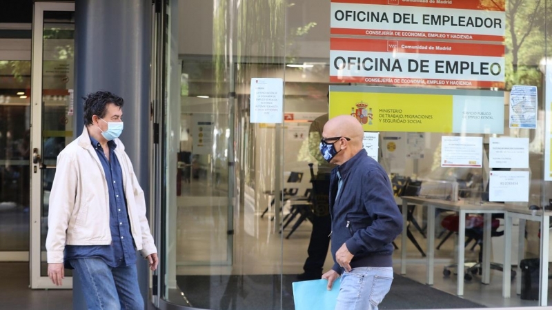 Dos personas con mascarilla pasan por una oficina de empleo de Madrid. E.P./Marta Fernández