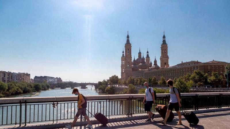 Varias personas con maletas cruzan el Puente de Santiago de Zaragoza. EFE/Javier Belver/Archivo