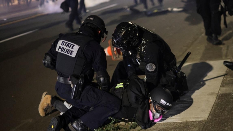 La policía detiene a un manifestante en la centésima noche consecutiva de protestas contra la violencia policial y la desigualdad racial, en Portland. REUTERS / Carlos Barria