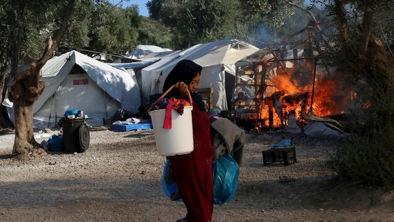 Una mujer trata de recuperar alguna de sus pertenencias, mientras el fuego sigue consumiendo las carpas del campamento de refugiados de Moria. - EFE