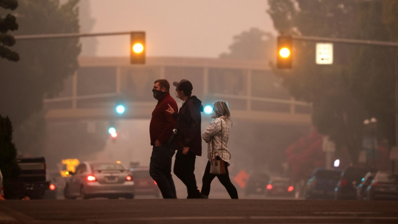 Local residents cross a street as smoke from wildfires covers an area near Salem, Oregon