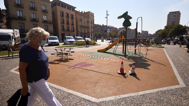 Una mujer pasea por una plaza de Girona, este miércoles en que el ayuntamiento de la ciudad ha tomado nuevas medidas para frenar la covid-19, cerrando parques infantiles. /EFE