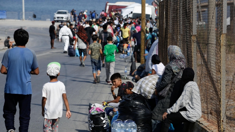 Refugiados y migrantes del destruido campamento de Moria hacen fila para ingresar a un nuevo campamento temporal durante una operación policial, en la isla de Lesbos. REUTERS / Elias Marcou