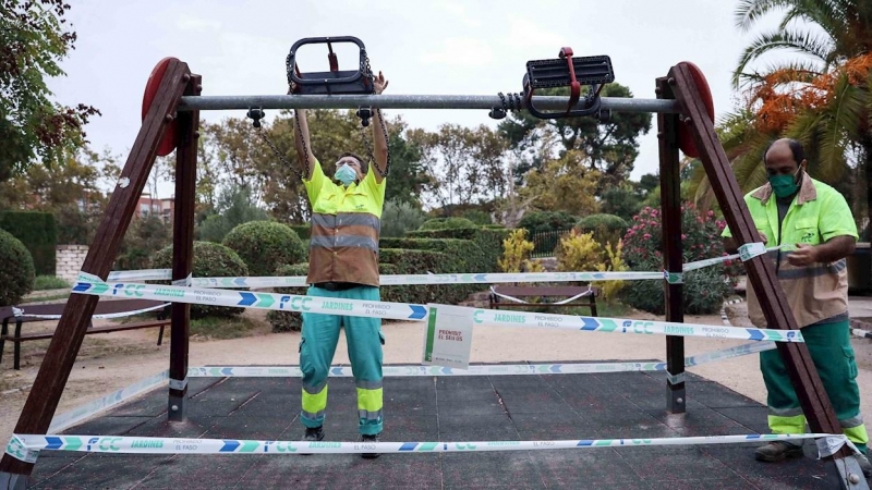 Varios operarios precintan unos columpios en un parque de Valencia este viernes, cuando se vuelven a cerrar temporalmente desde hoy las 664 zonas de juegos infantiles de los parques y jardines, como se hizo durante el estado de alarma. /EFE