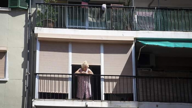 Una mujer sale a la terraza en uno de los barrios confinados / Getty Images