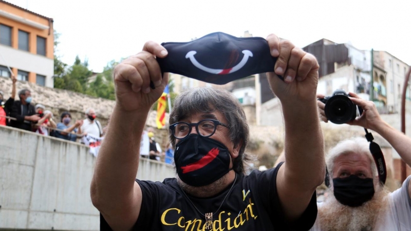 Jordi Pesarrodona aixecant una mascareta amb un somriure a les portes del jutjat de Manresa, on inicia la causa per la seva participació al referèndum de l'1 d'octubre. Mar Martí | ACN