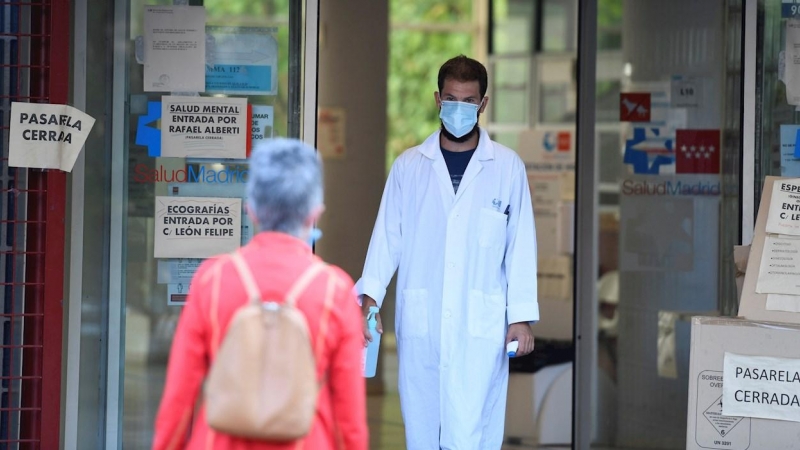 Un sanitario recibe a una paciente termómetro en mano en el centro de salud Federica Montseny en el distrito de Puente de Vallecas en Madrid.-EFE