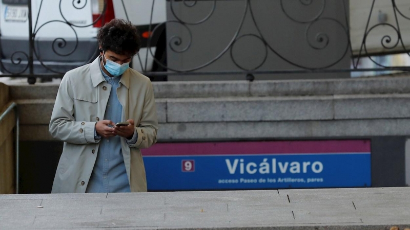 28/09/2020.- Un ciudadano consulta su teléfono a su salida de la estación de metro de Vicálvaro, este lunes. /EFE - CHEMA MOYA