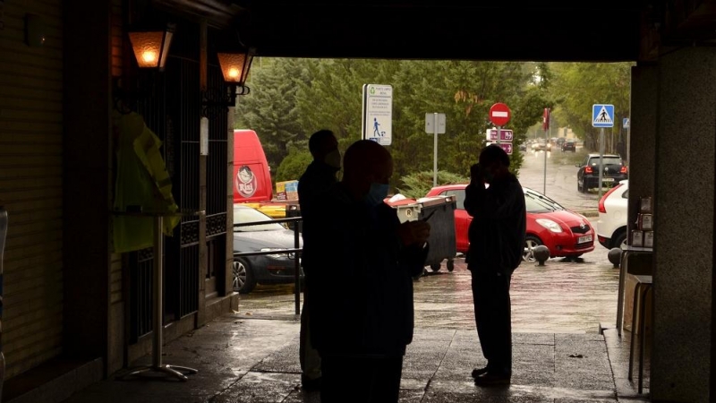 Los vecinos de El Pardo se refugian de la lluvia en unos soportales del centro. JOSE CARMONA.