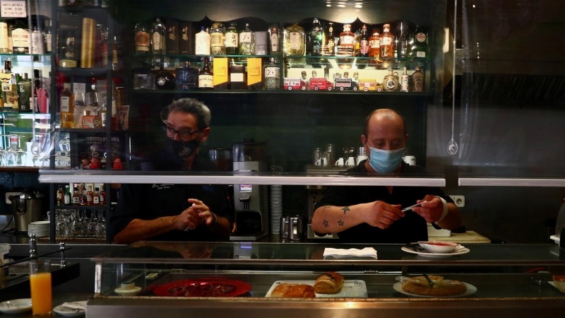 Dos camareros con mascarilla, tras la barra de un bar del madrileño barrio de Vallecas.  REUTERS/Sergio Perez