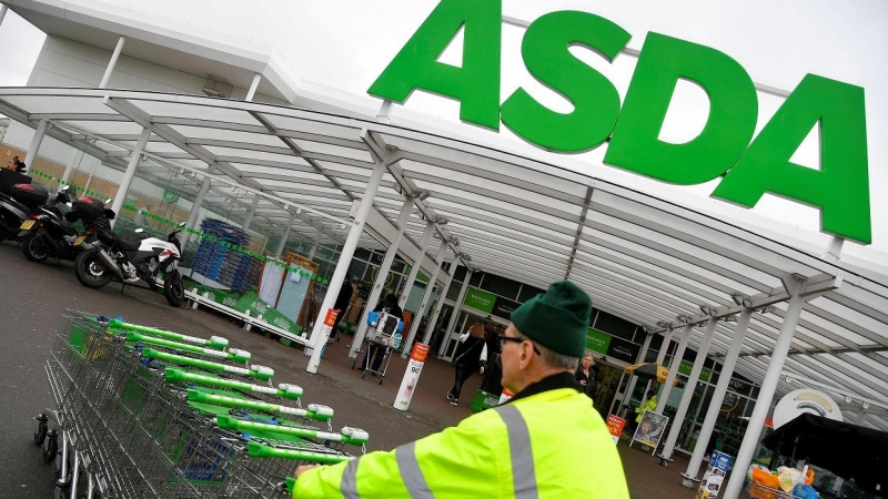 Un trabajador traslada una fila de carritos de la compra en un establecimiento de la cadena de supermercados británica Asda, en Londres. REUTERS/Toby Melville