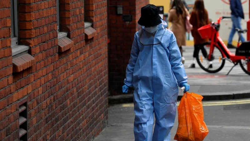 Una mujer camina protegida contra la covid.  REUTERS/Toby Melville