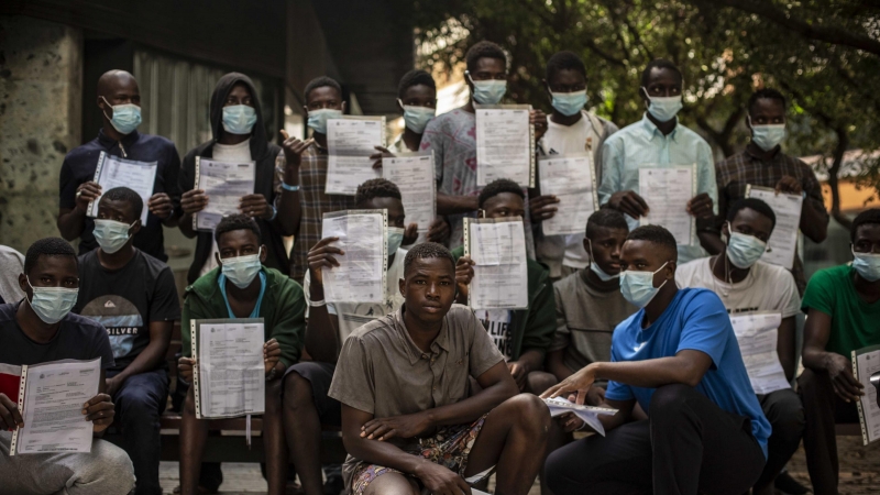 Un grupo de migrantes malienses muestra su expediente de devolución en una plaza de Las Palmas de Gran Canaria, cerca del centro de acogida en el que esperan más de un mes después de llegar en patera a la isla.- JAIRO VARGAS