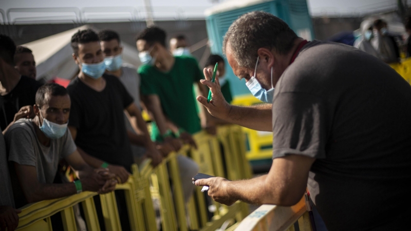 Un voluntario de Cruz Roja llama a los migrantes que podrán salir del puerto de Arguineguín, en Gran Canaria, tras varios días de espera.- JAIRO VARGAS