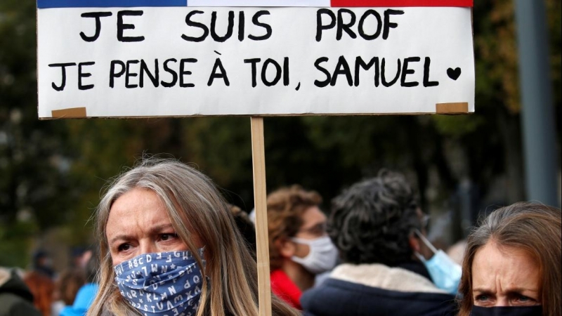 Una mujer sostiene una pancarta mientras asiste a un homenaje a Samuel Paty, el profesor de francés que fue decapitado en las calles del suburbio parisino de Conflans St Honorine, Francia. REUTERS / Pascal Rossignol / Archivo