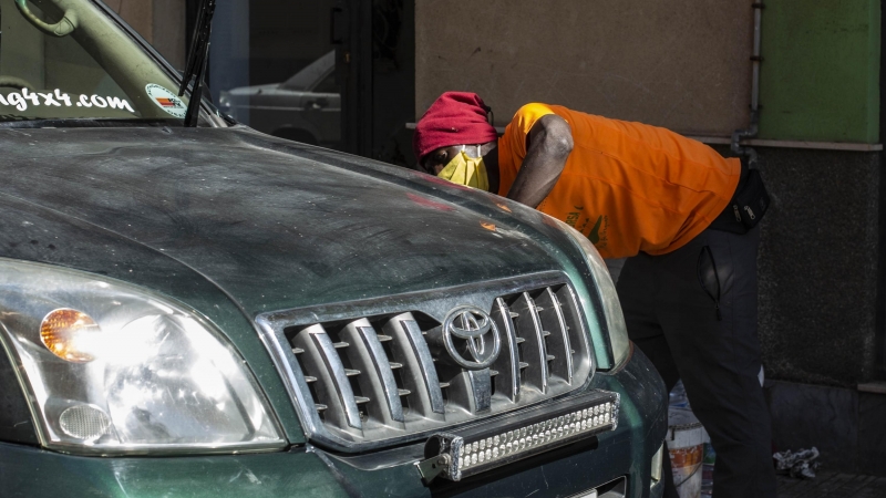 Un migrante lava un 4x4 por tres euros junto a la plaza de toros de Melilla, reconvertido en un CETI por saturación del centro durante la pandemia.- JAIRO VARGAS