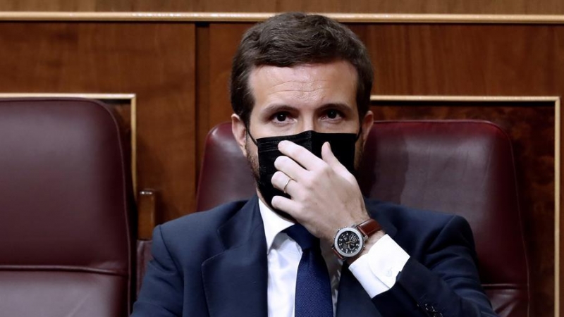 El líder del Partido Popular, Pablo Casado, se coloca la mascarilla mientras asisten a la moción de censura presentada por Vox al gobierno de coalición en el Congreso de los Diputados este miércoles. EFE/Mariscal