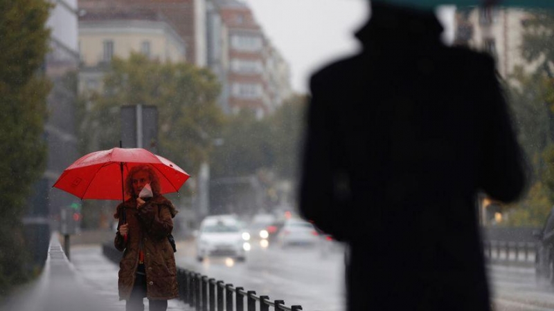 Dos transeúntes caminan entre la lluvia por las calles del centro de Madrid esta mañana de martes. EFE/ Mariscal