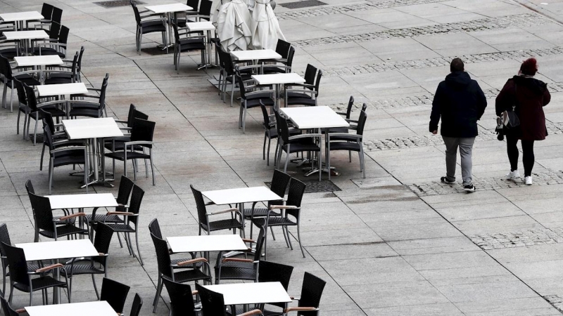 22/10/2020.- Dos personas caminan por la Plaza del Castillo de Pamplona que hoy jueves presenta un inusual aspecto con las terrazas de los bares vacías en una jornada en la que cientos de pamploneses salen este día 'Juevintxo', para compartir en la calle