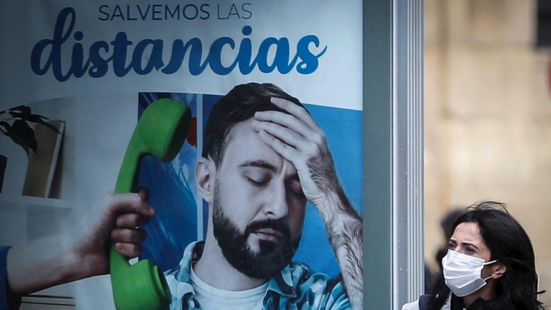 26/10/2020.- Una mujer pasa junto a un panel publicitario este lunes en San Sebastián. El alcalde donostiarra, Eneko Goia, ha informado hoy de que la ciudad ha entrado en 'zona roja' y se prepara para adoptar las restricciones impuestas a los municipios q