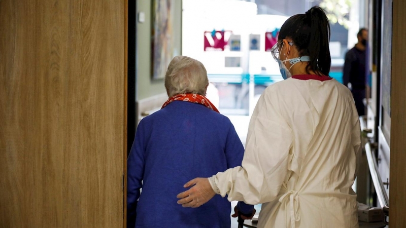 Una trabajadora de la residencia de mayores 'Vitalia Canillejas' ayuda a una paciente, este lunes en las instalaciones del centro, en Madrid. / EFE
