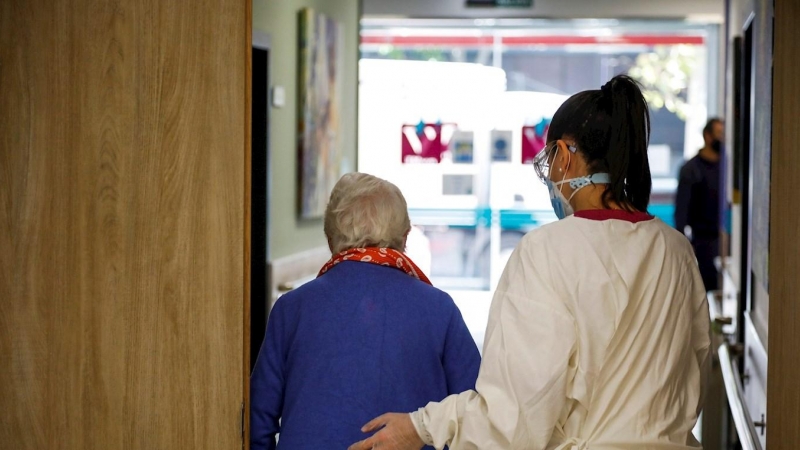 Una trabajadora de la residencia de mayores 'Vitalia Canillejas' ayuda a una paciente, este lunes en las instalaciones del centro, en Madrid. / EFE