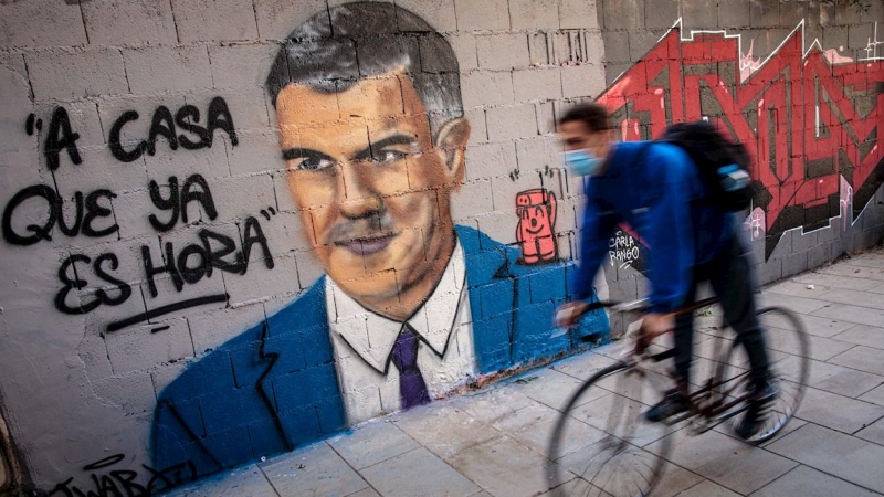 VALENCIA, 26/10/2020.Una persona en bicicleta pasa frente a una pintura mural del artista urbano J.Warx donde aparece el presidente del Gobierno, Pedro Sánchez, bajo la frase “A casa que ya es hora'.