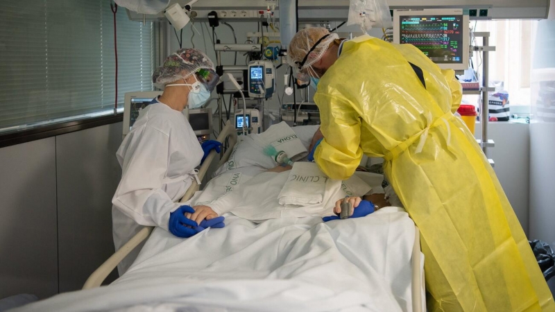 Dos sanitaris visiten un pacient de Covid-19 a l'UCI de l'Hospital Clínic protegits amb EPI. Francisco Àvia | ACN
