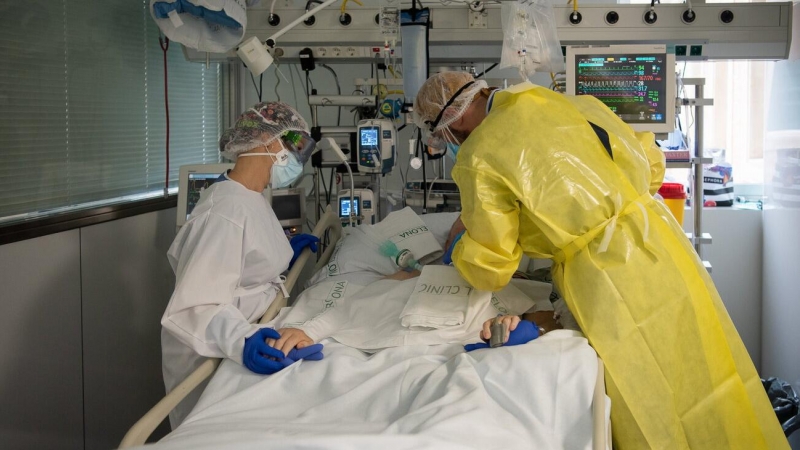 Dos sanitaris visiten un pacient de Covid-19 a l'UCI de l'Hospital Clínic protegits amb EPI. Francisco Àvia | ACN