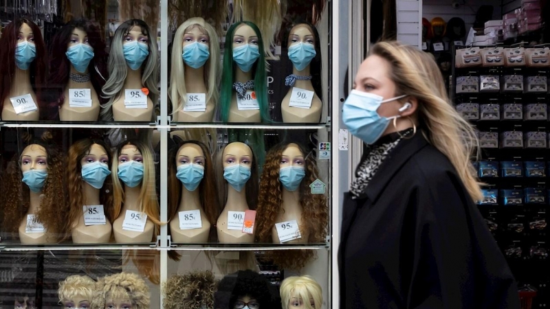 Una mujer con mascarilla pasa frente a un escaparate en París.