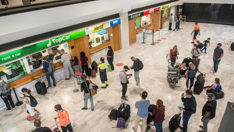 Varios turistas hacen cola ante una oficina de alquiler de vehículos a su llegada al aeropuerto César Manrique de Lanzarote.