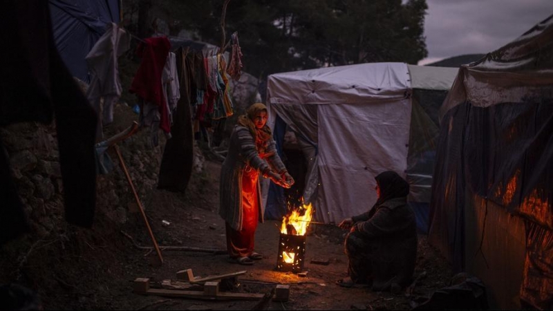 Una refugiada se calienta en un fuego en el campo de acogida de Samos.