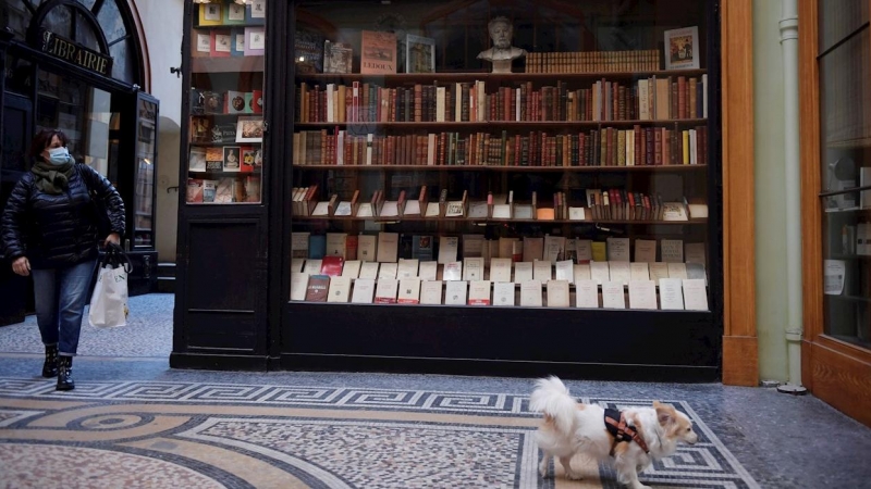 Una mujer y su perro frente a una librería en París.