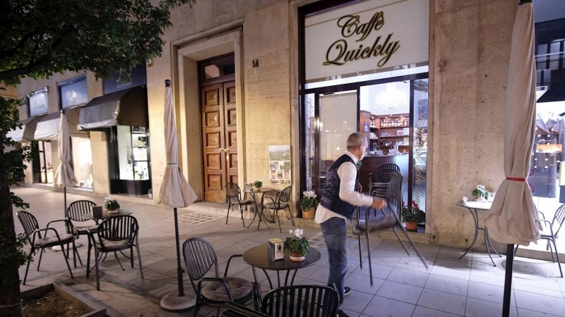 Un propietario se prepara para cerrar su restaurante en el centro de Turín.