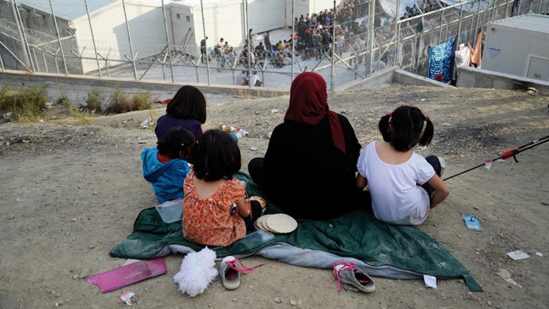 Una mujer observa con sus hijos el campamento de Moria.