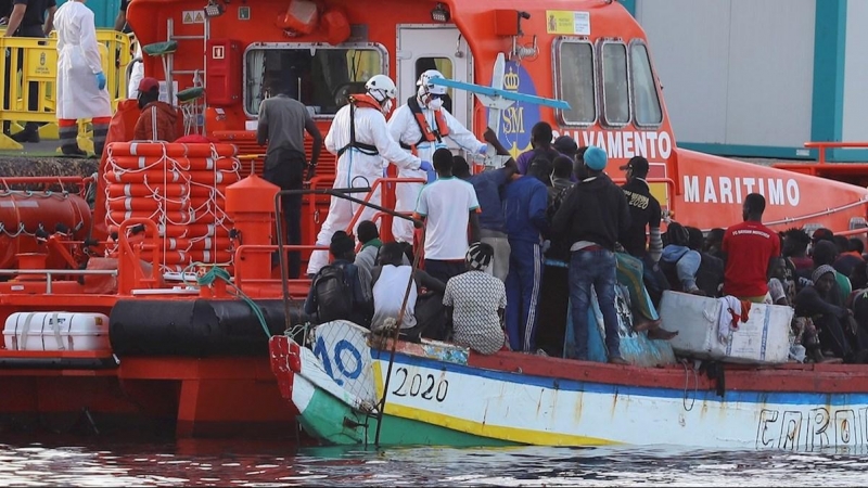El personal de Salvamento Marítimo ayuda a los inmigrantes a desembarcar en el puerto de Arguineguín.