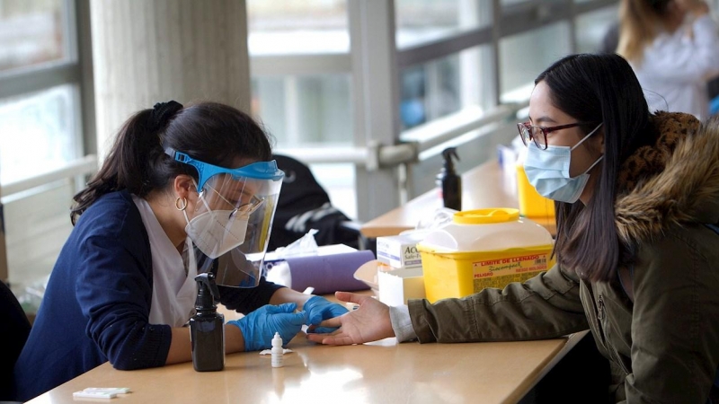 Una estudiante de Enfermería (i) realiza un test rápido de SARS-CoV-2