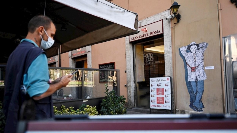 Un hombre pasea frente a una cafetería en Roma, italia.