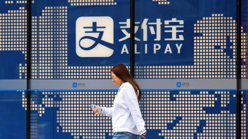 Una mujer pasa junto al logo del sistema de pago electrónico Alipay, de Ant Group, en un edificio en Shanghai. EFE/EPA/ALEX PLAVEVSKI