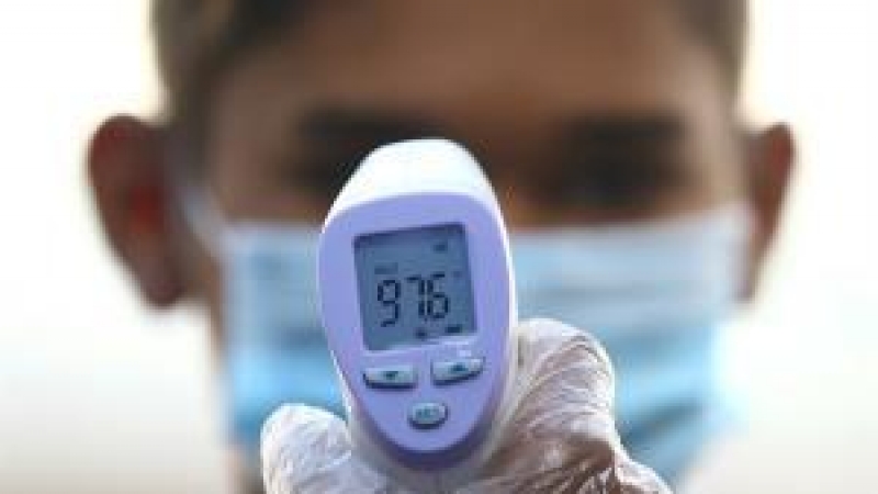 Imagen de archivo de un sanitario tomando la temperatura.