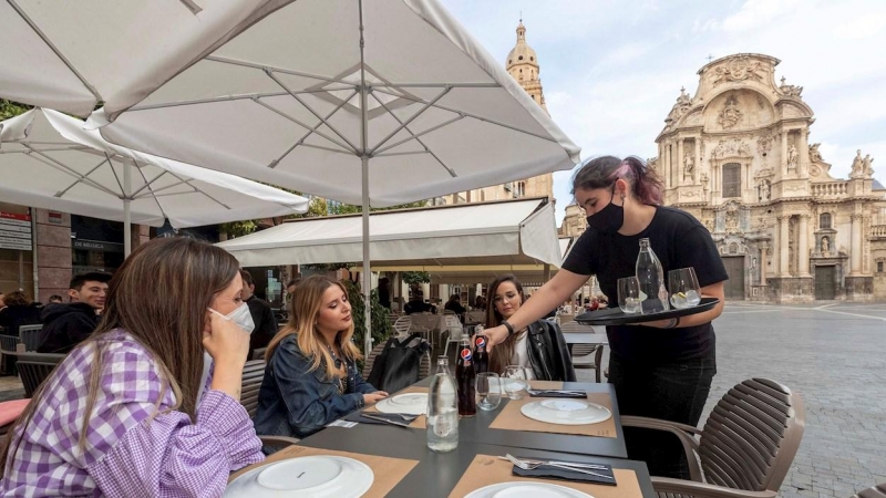 Una camarera sirve la bebida en la mesa de la terraza de un restaurante este miércoles en la Plaza Cardenal Belluga de Murcia.