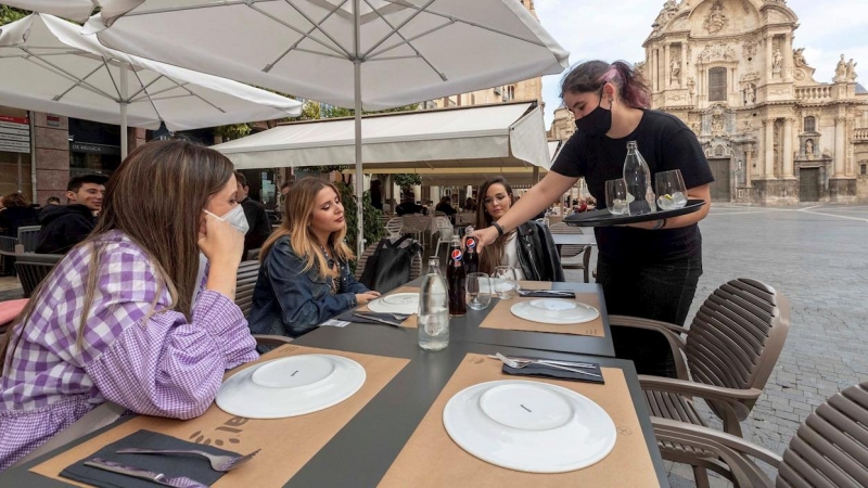 Una camarera sirve la bebida en la mesa de la terraza de un restaurante este miércoles en la Plaza Cardenal Belluga de Murcia.