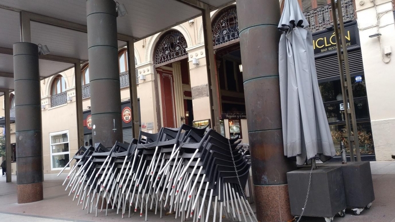 Las sillas y mesas de un bar cerrado cogen polvo a la espera de tiempos más prósperos en una céntrica plaza de Zaragoza.