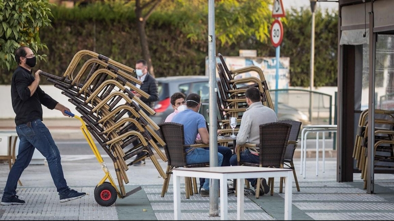 Camareros de un bar de Mairena del Aljarafe(Sevilla) recogen el mobiliario para proceder al cierre antes de las seis de la tarde