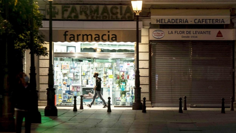 Un hombre pasa junto a una farmacia abierta